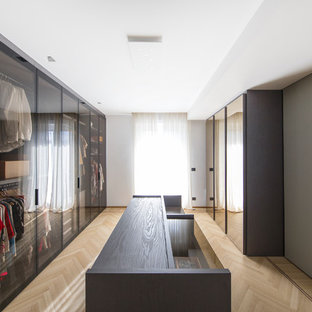 Ispirazione per uno spazio per vestirsi minimal con ante di vetro, parquet chiaro e pavimento beige