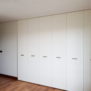Modern inredning av en mellanstor garderob för könsneutrala, med mellanmörkt trägolv