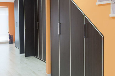 Ejemplo de armario vestidor moderno grande con armarios con paneles empotrados y puertas de armario de madera en tonos medios
