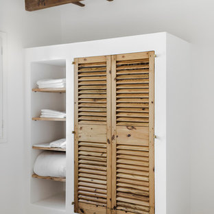 Inspiration för små medelhavsstil klädskåp för könsneutrala, med skåp i ljust trä, betonggolv och luckor med lamellpanel