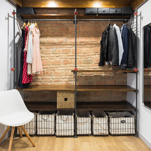 Immagine di una piccola cabina armadio unisex industriale con nessun'anta, ante in legno bruno e parquet chiaro