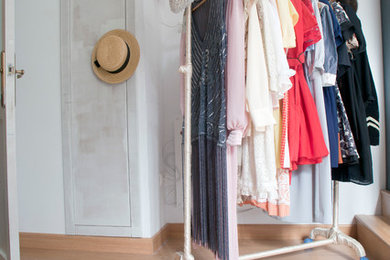Imagen de vestidor unisex nórdico pequeño con armarios abiertos, puertas de armario blancas y suelo de madera clara