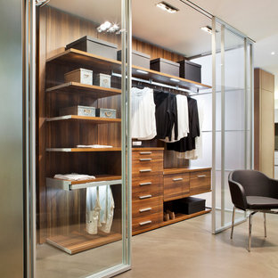 Idéer för mellanstora funkis walk-in-closets för kvinnor, med luckor med glaspanel, betonggolv och beiget golv