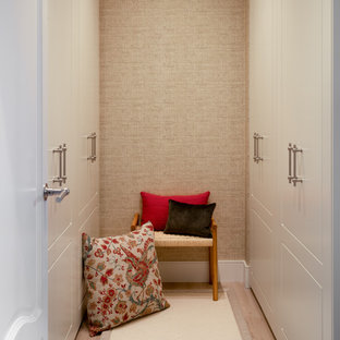 Modelo de armario vestidor unisex, actual, pequeño, con armarios con paneles con relieve, puertas de armario blancas, suelo laminado y suelo beige