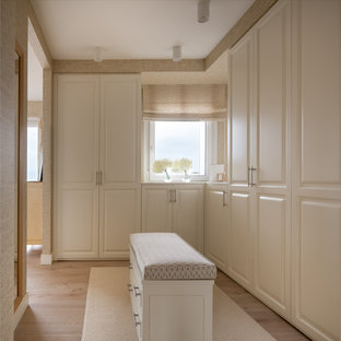 Modelo de vestidor unisex, clásico renovado, grande, con armarios con paneles con relieve, puertas de armario blancas, suelo laminado y suelo marrón