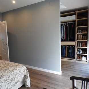 Esempio di una cabina armadio unisex nordica di medie dimensioni con pavimento in legno massello medio, nessun'anta e ante in legno chiaro