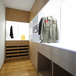 Ejemplo de armario vestidor contemporáneo, de tamaño medio, con armarios con paneles lisos, puertas de armario de madera clara y suelo de madera clara