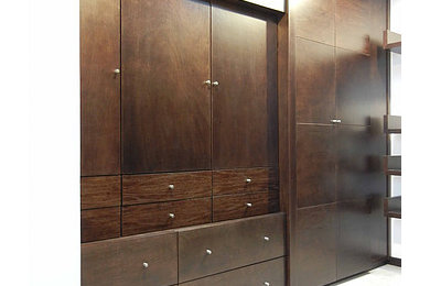 Imagen de vestidor unisex minimalista de tamaño medio con armarios con paneles lisos, puertas de armario de madera en tonos medios y suelo de madera oscura