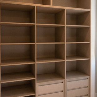 Imagen de armario vestidor unisex, moderno, con armarios abiertos, puertas de armario marrones, suelo de madera en tonos medios y suelo marrón