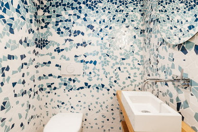 Ispirazione per un piccolo bagno di servizio stile marinaro con nessun'anta, ante in legno scuro, WC sospeso, piastrelle blu, piastrelle bianche, piastrelle a mosaico, pavimento in legno massello medio, lavabo rettangolare, top in legno, pavimento marrone e top marrone