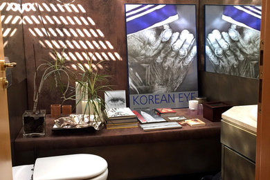 Imagen de aseo bohemio pequeño con armarios con paneles lisos, sanitario de pared, paredes marrones y lavabo encastrado