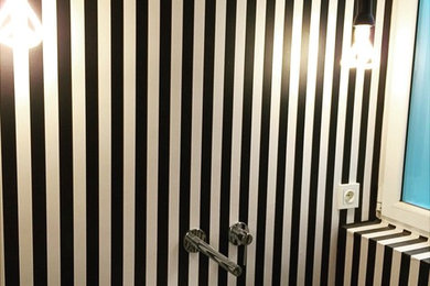 Diseño de aseo escandinavo de tamaño medio con sanitario de pared, paredes multicolor, suelo de madera clara, lavabo sobreencimera y encimera de madera