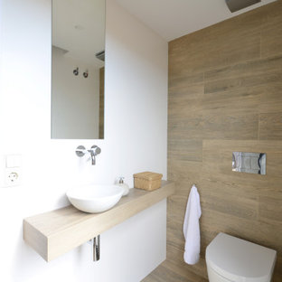 Imagen de aseo flotante, contemporáneo, de tamaño medio, con baldosas y/o azulejos beige, baldosas y/o azulejos de porcelana, paredes blancas, suelo de baldosas de porcelana, lavabo sobreencimera, encimera de madera, suelo beige y encimeras beige