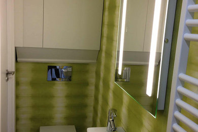 Modelo de aseo contemporáneo pequeño con sanitario de pared, paredes verdes y lavabo suspendido