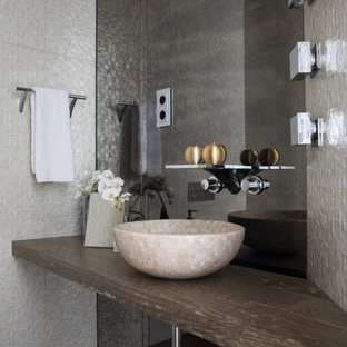 Foto de aseo contemporáneo, de tamaño medio, con armarios abiertos, puertas de armario de madera oscura, baldosas y/o azulejos de vidrio laminado, suelo de madera oscura, lavabo sobreencimera, encimera de madera, suelo marrón y encimeras marrones