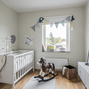 Inredning av ett minimalistiskt mellanstort könsneutralt babyrum, med beige väggar, ljust trägolv och beiget golv