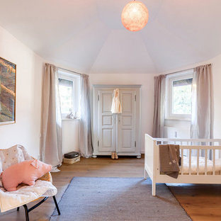 Mittelgroßes, Neutrales Nordisches Babyzimmer mit weißer Wandfarbe, braunem Holzboden und braunem Boden in München