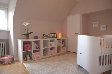 Mittelgroßes Modernes Babyzimmer mit rosa Wandfarbe und hellem Holzboden in Köln