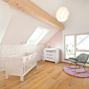 Großes Modernes Babyzimmer mit weißer Wandfarbe, hellem Holzboden und braunem Boden in Stuttgart