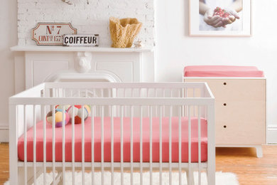 Diseño de habitación de bebé niña actual con paredes blancas y suelo de madera pintada