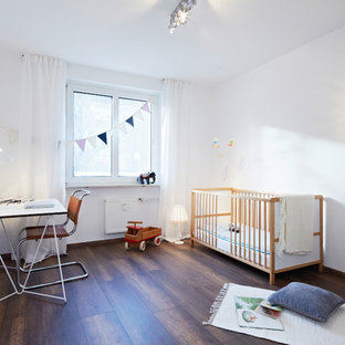 Mittelgroßes Modernes Babyzimmer mit weißer Wandfarbe, dunklem Holzboden und braunem Boden in Nürnberg