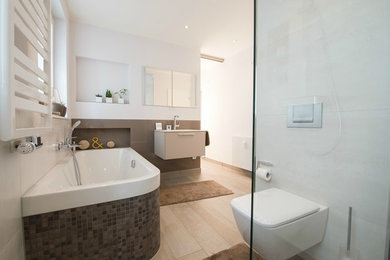 Immagine di un'ampia stanza da bagno padronale contemporanea con vasca da incasso, doccia a filo pavimento, WC sospeso, lavabo sospeso, ante lisce, ante beige, pareti bianche e parquet chiaro