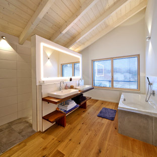 Mittelgroßes Country Badezimmer En Suite mit offenen Schränken, Einbaubadewanne, Nasszelle, grauen Fliesen, Aufsatzwaschbecken, Waschtisch aus Holz, offener Dusche, brauner Waschtischplatte, weißer Wandfarbe, braunem Holzboden, braunem Boden und dunklen Holzschränken in München