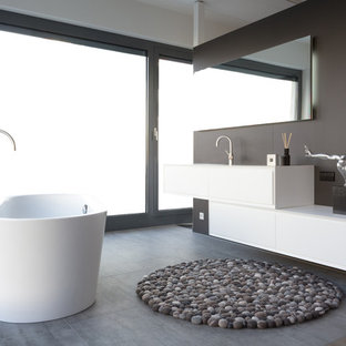 Kleines Modernes Badezimmer En Suite mit flächenbündigen Schrankfronten, weißen Schränken, freistehender Badewanne, braunen Fliesen, integriertem Waschbecken, Beton-Waschbecken/Waschtisch, grauem Boden und weißer Waschtischplatte in Sonstige