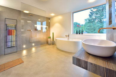 Großes Modernes Duschbad mit freistehender Badewanne, offener Dusche, weißer Wandfarbe, Betonboden, Aufsatzwaschbecken, Waschtisch aus Holz, grauem Boden, offener Dusche und brauner Waschtischplatte in Sonstige
