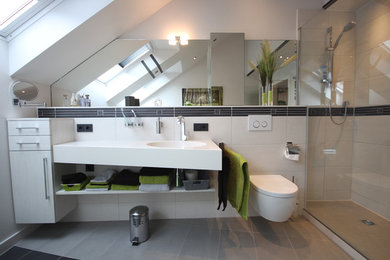Mittelgroßes Modernes Duschbad in Dachschräge mit integriertem Waschbecken, Wandtoilette, grauen Fliesen, Porzellanfliesen, grauer Wandfarbe und Porzellan-Bodenfliesen in Köln