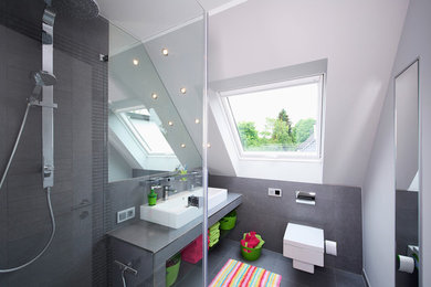 Cette image montre une salle de bain design avec une douche à l'italienne, un carrelage gris et un mur blanc.