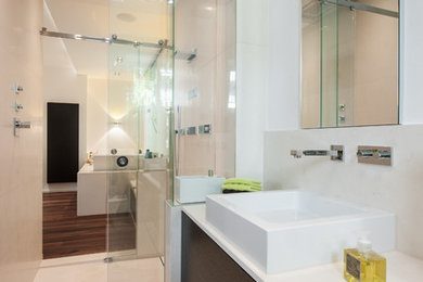 Modelo de cuarto de baño actual con puertas de armario blancas, ducha a ras de suelo, paredes blancas y suelo de madera en tonos medios