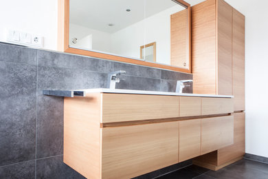 Mittelgroßes Modernes Badezimmer En Suite mit flächenbündigen Schrankfronten, hellbraunen Holzschränken, Keramikboden und grauem Boden in München