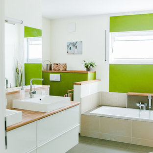 Mittelgroßes Modernes Badezimmer mit weißen Schränken, Einbaubadewanne, offener Dusche, Wandtoilette mit Spülkasten, beigefarbenen Fliesen, Keramikfliesen, grüner Wandfarbe, Porzellan-Bodenfliesen, Aufsatzwaschbecken, Mineralwerkstoff-Waschtisch, grauem Boden und brauner Waschtischplatte in Nürnberg