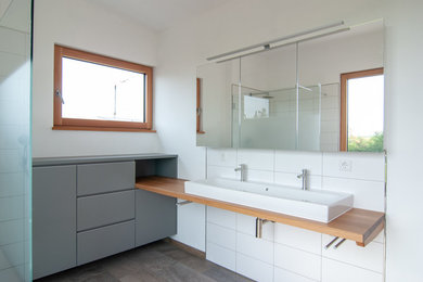 Mittelgroßes Modernes Duschbad mit flächenbündigen Schrankfronten, weißer Wandfarbe, Aufsatzwaschbecken, Waschtisch aus Holz und brauner Waschtischplatte in Sonstige