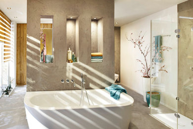На фото: главная ванная комната в современном стиле с отдельно стоящей ванной, душем без бортиков, белыми стенами и бетонным полом с