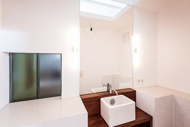 Mittelgroßes Modernes Badezimmer mit offenen Schränken, braunen Schränken, weißen Fliesen, Keramikfliesen, weißer Wandfarbe, Aufsatzwaschbecken, Waschtisch aus Holz und brauner Waschtischplatte in Köln