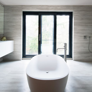Mittelgroßes Modernes Badezimmer mit flächenbündigen Schrankfronten, weißen Schränken, freistehender Badewanne, beigefarbenen Fliesen und beigem Boden in Hamburg