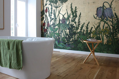Foto på ett funkis en-suite badrum, med ett fristående badkar, flerfärgade väggar och ljust trägolv