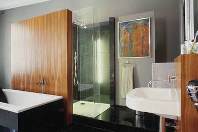 Ejemplo de cuarto de baño actual grande con bañera exenta, ducha empotrada, baldosas y/o azulejos negros, paredes grises y lavabo suspendido