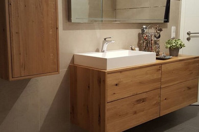 Cette photo montre une petite salle de bain principale moderne en bois clair avec un placard à porte plane.
