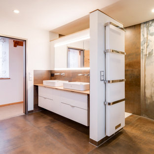 Großes Asiatisches Duschbad mit flächenbündigen Schrankfronten, weißen Schränken, braunen Fliesen, weißer Wandfarbe, Aufsatzwaschbecken, Waschtisch aus Holz, braunem Boden und beiger Waschtischplatte in Sonstige