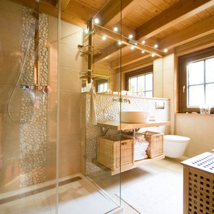 Mittelgroßes Mediterranes Badezimmer En Suite mit offenen Schränken, bodengleicher Dusche, Wandtoilette, beigefarbenen Fliesen, beiger Wandfarbe, Porzellan-Bodenfliesen, Aufsatzwaschbecken, Waschtisch aus Holz, hellen Holzschränken, Kieselfliesen und Schiebetür-Duschabtrennung in Bremen