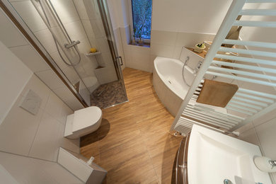This is an example of a medium sized country bathroom in Dresden with dark wood cabinets, a corner bath, a built-in shower, a two-piece toilet, white tiles, ceramic tiles, white walls, ceramic flooring, a built-in sink and solid surface worktops.