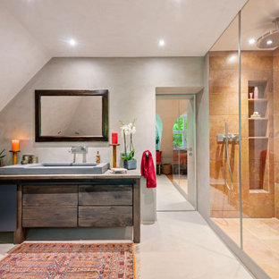 Großes Kolonialstil Badezimmer mit dunklen Holzschränken, Eckbadewanne, bodengleicher Dusche, beigefarbenen Fliesen, Travertinfliesen, beiger Wandfarbe, Betonboden, Aufsatzwaschbecken, Beton-Waschbecken/Waschtisch, beigem Boden, offener Dusche, brauner Waschtischplatte, Einzelwaschbecken, freistehendem Waschtisch und gewölbter Decke in München