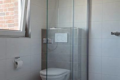 Modernes Badezimmer mit weißen Schränken, bodengleicher Dusche, Wandtoilette mit Spülkasten, weißen Fliesen, Keramikfliesen, weißer Wandfarbe und Unterbauwaschbecken in Berlin