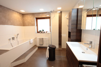 シュトゥットガルトにある高級な中くらいなおしゃれな浴室 (濃色木目調キャビネット、ドロップイン型浴槽、バリアフリー、壁掛け式トイレ、白いタイル、オーバーカウンターシンク、開き戸のシャワー、洗面台1つ、造り付け洗面台) の写真