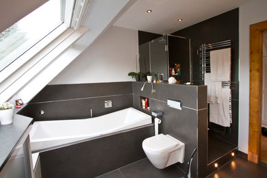 Modelo de cuarto de baño actual pequeño con paredes blancas, ducha empotrada, baldosas y/o azulejos negros, bañera empotrada y sanitario de pared