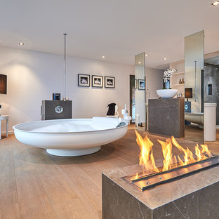 Foto de cuarto de baño principal, actual, extra grande, con bañera exenta, paredes blancas, suelo de madera en tonos medios, lavabo sobreencimera y suelo marrón