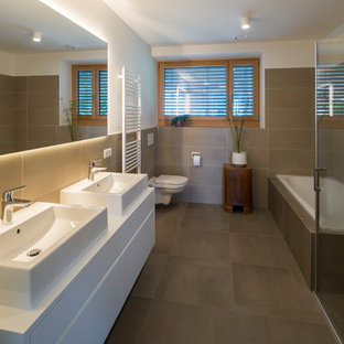 Ispirazione per una stanza da bagno padronale minimalista con ante lisce, vasca da incasso, doccia ad angolo, WC sospeso, piastrelle beige, pareti bianche, lavabo a bacinella, pavimento beige, porta doccia a battente e top bianco
